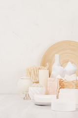 Organic homemade white cosmetics and beige wooden bamboo bath accessories on white wooden background, border.