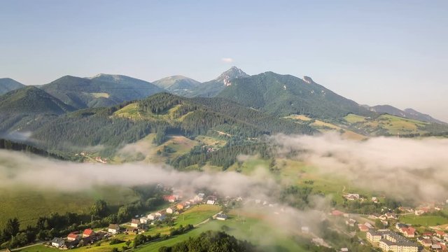 Foggy morining in green mountains over rural country. Aerial Time lapse