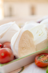 Fresh soft Italian white cheese mozzarella buffalo, original from Campania, Paestrum and Foggia regions, South Italy, served with tomatoes and fresh basil