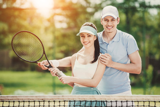 Happy Couple Standing on Tennis Court with Rackets