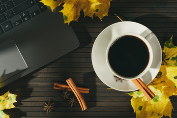 Composition of laptop and coffee cup in leaves