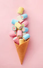 Wall murals Sweets Marshmallow candy colorful assortment in an ice cream cone on a pink background viewed from above. Gummy candy variation. Top view