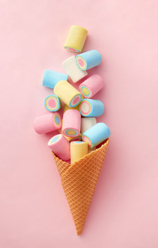 Marshmallow candy colorful assortment in an ice cream cone on a pink background viewed from above. Gummy candy variation. Top view