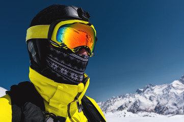 Close-up portrait of a skier in a mask and helmet with a closed face against a background of...