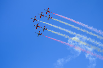 Red aircrafts aerobatic group drawing Spanish flag figure in the sky