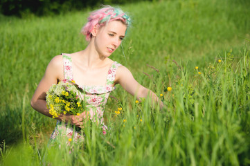 Portrait of a young happy smiling girl in a cotton dress with a bouquet of wildflowers