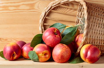 Nectarines in a wicker basket on a wooden table.