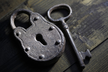 Antique padlock with key on wooden background