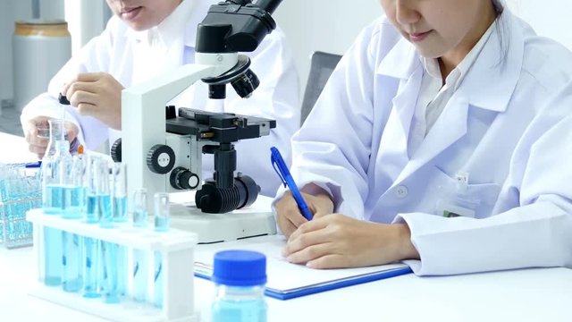 Asian Scientist working together at laboratory. People with medical, science, doctor, healthcare concept. Close up to microscope. 4K Resolution.