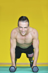 Obraz premium Strong attractive man performs exercises using a resistance band. Photo of muscular male isolated on yellow background. Strength and motivation