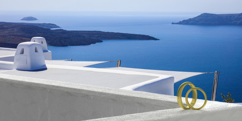 Wedding at Santorini, Greece. Wedding rings on whitewashed wall, volcano view background. 3d...