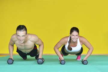 Beautiful fitness young sporty couple doing push ups together indoors.