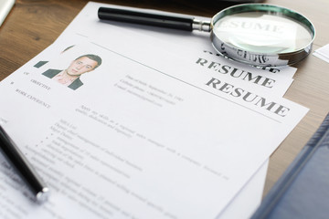 Resume (curriculum vitae, cv) and pen on a written wooden table. 