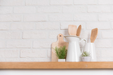 Kitchen utensils and dishware on wooden shelf. Kitchen interior background