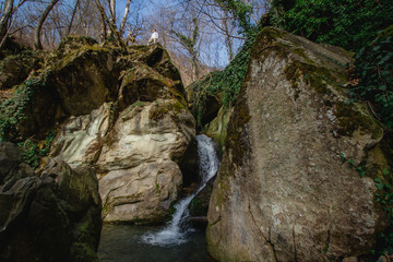 Tourism in mountains. Man standing on top of waterfall. Active lifestyle in nature.
