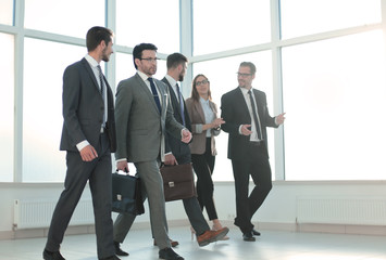 Businesspeople walking in the office background.