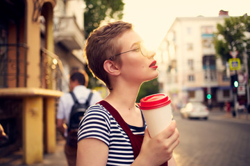 woman in glasses with coffee on the sunset street