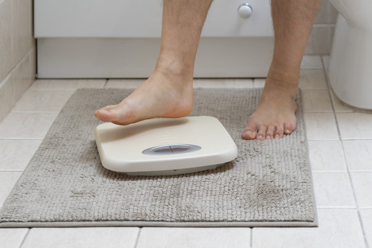 Cropped image of man feet stepping on weigh scale