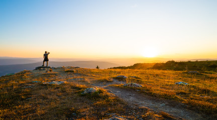 View over the hills at sundown, man watching