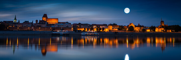 Obraz premium Old town reflected in river at sunset. Torun, Poland.