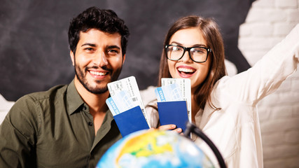Young couple smiling with the globe map and passports, they choosing place for travel