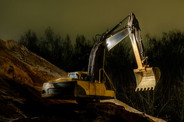 The yellow excavator works at night in the headlights and additional lights. Loads of sand. Night...