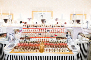 Delicious and tasty dessert table with cupcakes shots at reception closeup