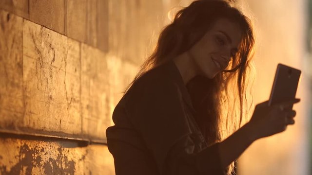 Video portrait of an attractive Caucasian white girl with beautiful hair. Happy girl in the underpass makes selfi on the smartphone.