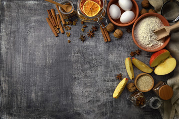 Flour, nuts, cinnamon, raisins, apples, eggs on a wooden background. Top view. Home cooking. Rustic style. Organic food.
