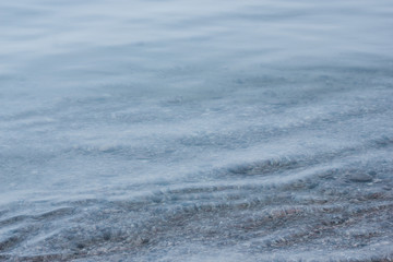 Closeup shot of calm clear blue wavy lake Baikal water and stony underwater beach. Atmospheric gradient marine picture, concept of tranquility, pure