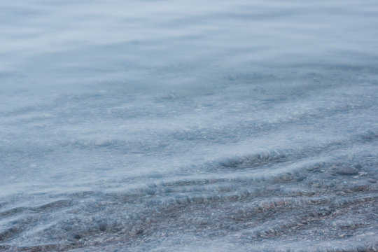 Closeup shot of calm clear blue wavy lake Baikal water and stony underwater beach. Atmospheric gradient marine picture, concept of tranquility, pure