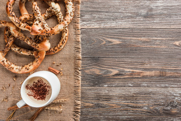 Fototapeta premium Composition of pretzels with decoration of a cappucino cup on wooden table