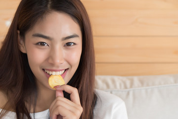 happy, smiling woman eating potato chips or crispy fried potato; unhealthy food or fried food concept; young adult asian persian woman or asian middle east model