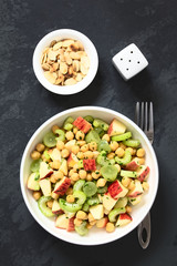 Fresh vegan chickpea, celery, grape and apple salad with parsley, roasted almond slices on the side, photographed overhead on slate with natural light (Selective Focus, Focus on the salad)