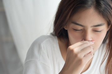 sick girl sniffle with runny nose; sick woman suffering from cold, flu, runny nose, trying to clear her nose; woman personal health care, pain, sickness concept; asian young adult woman model