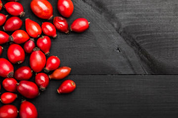 Rosehip on the black wooden table. Ingredient for medicinal tea, top view