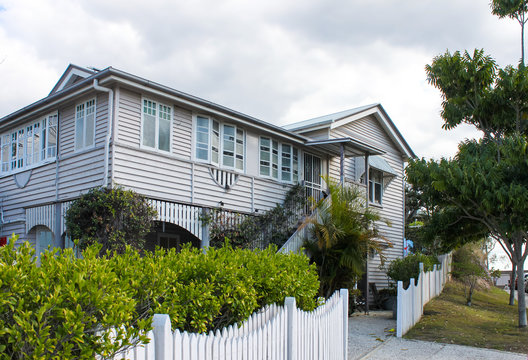 Typical Queensland House With Tropical Foliage And White Picket Fence On Overcast Day In Australia