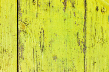 Abstract background of vertical acid yellow wooden boards. Bright green closeup shot of old country fence