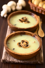 Mushroom cream soup garnished with roasted mushroom slices served in wooden bowls, photographed...