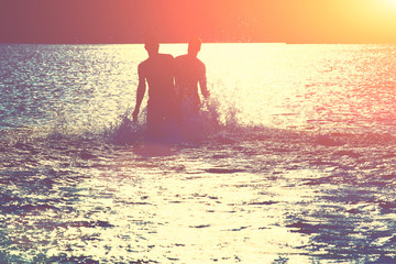 Glückliche junge Menschen laufen und springen am See beim Sonnenuntergang