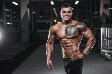 Fototapeta na wymiar Handsome strong bodybuilder athletic men pumping up muscles with dumbbells