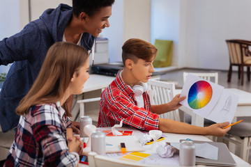 Art students. Promising creative art students feeling curious while looking at color palette choosing suitable color