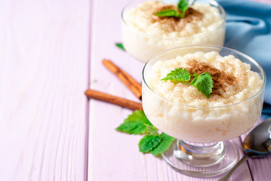Rice pudding with cinnamon and mint on light purple wooden background
