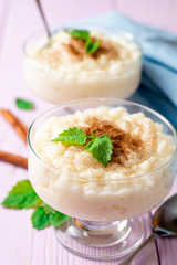 Rice pudding with cinnamon and mint on light purple wooden background