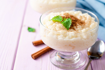 Rice pudding with cinnamon and mint on light purple wooden background