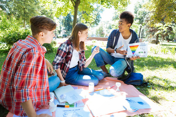 Art project. Team of smart creative undergraduates working on their art project while spending their time in nature