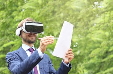 Happy bearded businessman with virtual reality glasses signs documents. Electronic signature, Future technology or Freelance concept