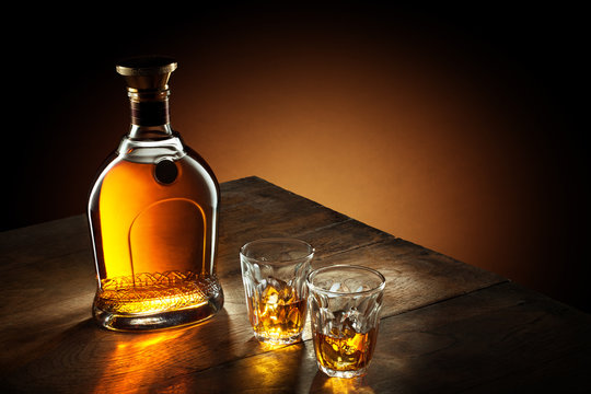 view of glasses of  bourbon  and a bottle aside on color background