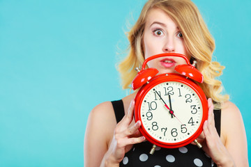 Shocked girl with alarm clock on blue.