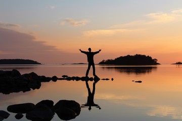 Silhouette of young man embracing the sunset